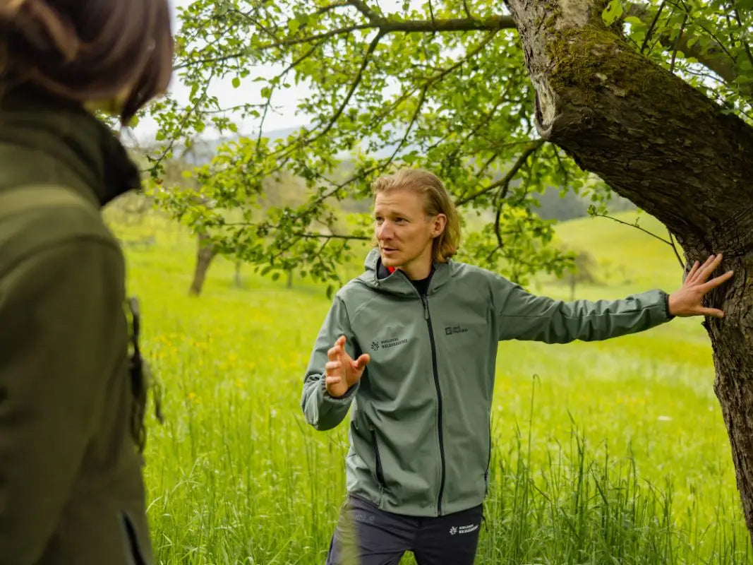 Waldexpertin erklärt einer Gruppe einen Baum am Waldrand