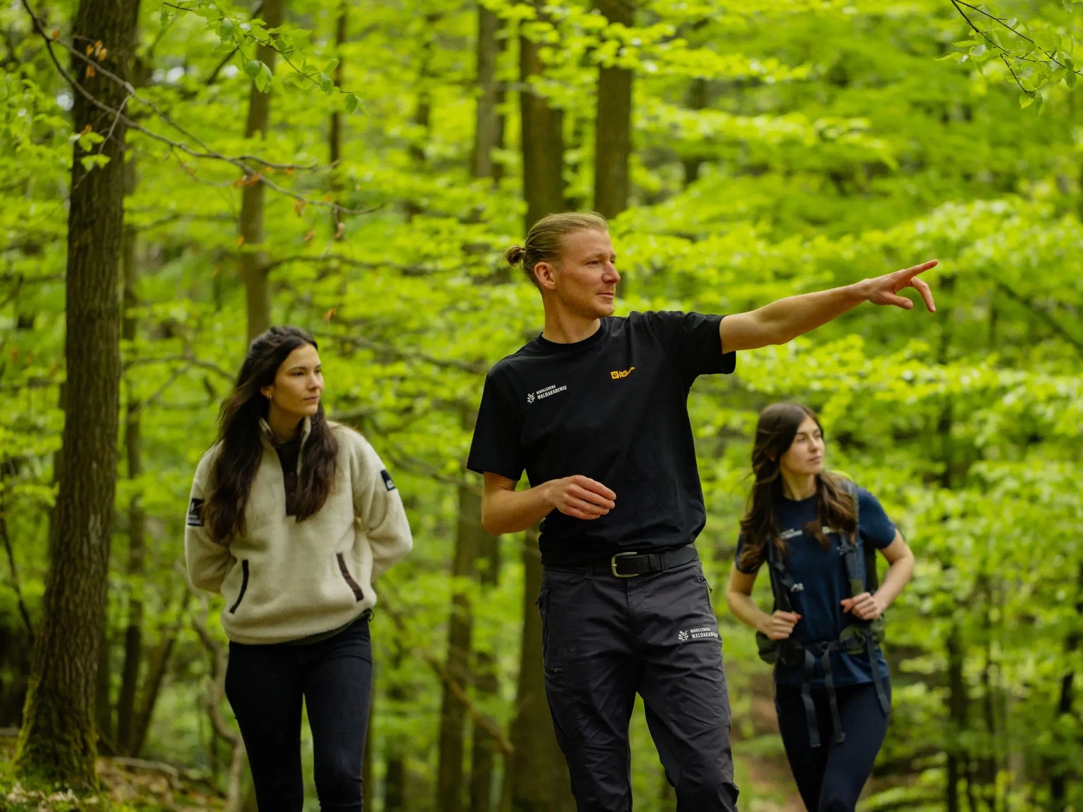 Ein Mann tauscht sich mit zwei Frauen in einem üppigen Wald während des UrwaldProjekts von Wohllebens Waldakademie über alte Wälder aus.