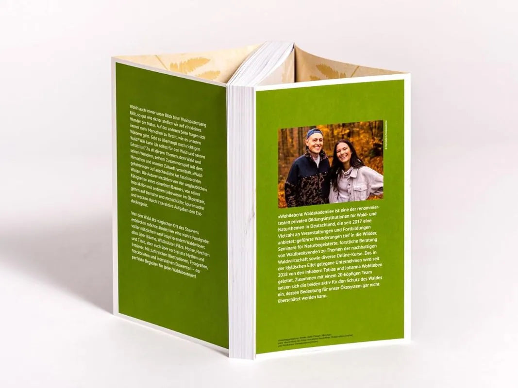 Ein aufrechtes grünes Buch von Wohllebens Waldakademie mit dem Titel "Waldgeheimnisse" zeigt auf der Rückseite einen Text und ein Foto von zwei lächelnden Menschen, die auf Geschichten über Bäume und Waldwunder hinweisen.